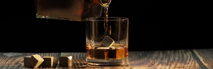 Whisky wird in Glas mit Whisky Eiswürfel geschenkt auf dunklem Hintergrund