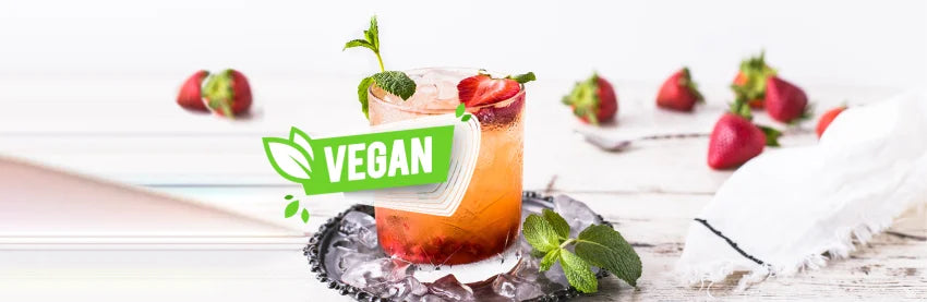 Schriftzug Vegan mit Cocktail und Erdbeeren als Deko