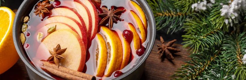 Glühwein mit Apfelscheiben, Zimtstangen und Anis sowie Tannenzweigen