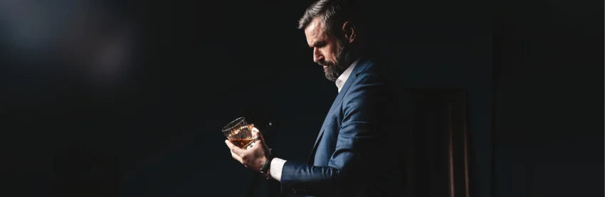 Mann mit Whisky Glas auf dunklem Hintergrund