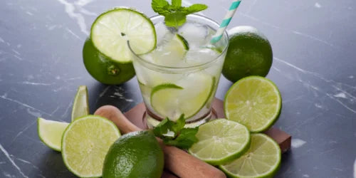 Caipirinha auf hellem Hintergrund mit Limetten und Strohhalm 