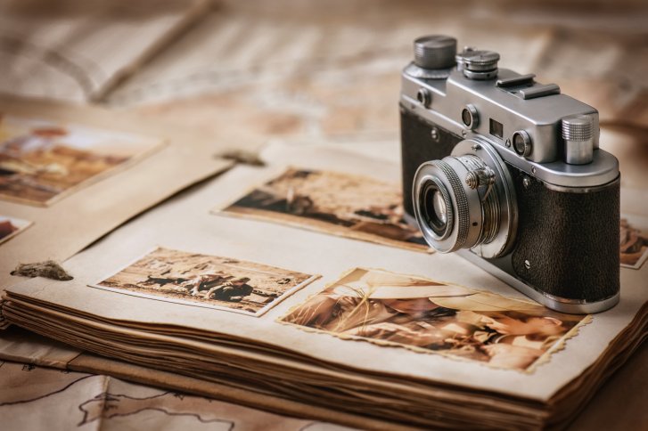L'appareil photo est posé sur un album de vieilles photos dans une ambiance nostalgique.
