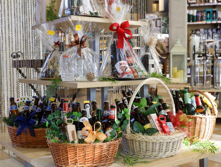 Manden met bierflesjes, versierd met strikken, staan op houten tafels in een winkel.