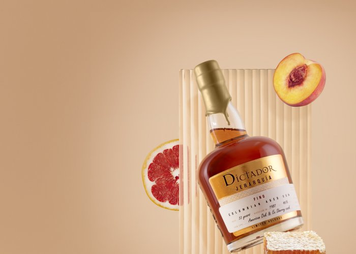 Fles rum met gouden etiket drijft tegen een achtergrond van perzik, honing en grapefruit.