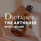 Fles ligt diagonaal op gelaagde stof, tekst: "Dictador The Arthouse Spirit Brand".
