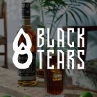 Fles rum en glas op houten tafel voor plant, tekst: "Black Tears".