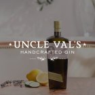 Fles gin staat op tafel, omringd door citroen, komkommer en lavendel. Tekst: "UNCLE VAL'S HANDCRAFTED GIN".