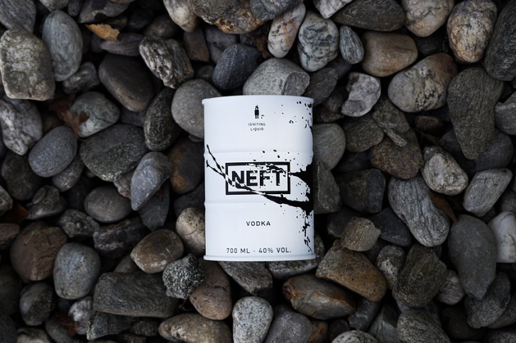 Weiße NEFT-Wodkaflasche liegt auf verschiedenen glatten Steinen. Text: 700 ml, 40% Vol.