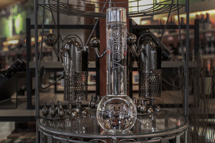 Vodkaflasche steht auf einem Tisch, umgeben von futuristischen Metallskulpturen im Laden.