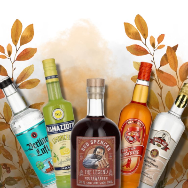Five colorful bottles of spirits stand in front of an autumnal background with leaves.