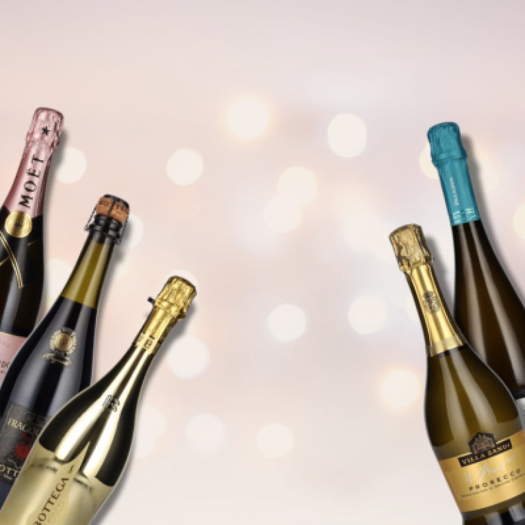 5 Schaumwein-Flaschen vor hellem Hintergrund.