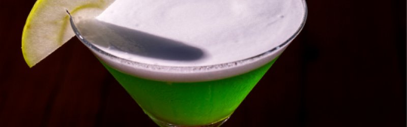 apple martini im martini glas mit Garnitur auf dunklem Hintergrund