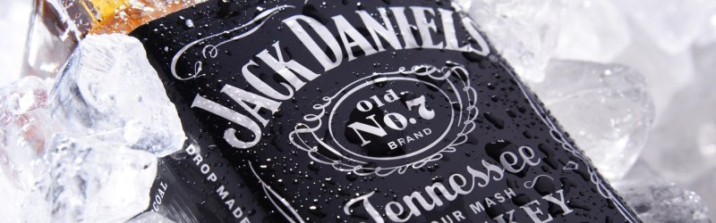 Flasche Jack Daniel's, liegend im Eis, mit Wassertropfen bedeckt, Etikett klar erkennbar.