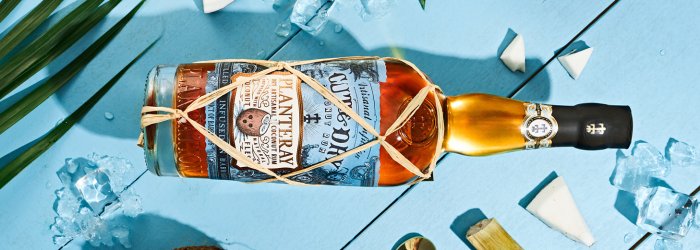 Une bouteille de rhum sur un tonneau en bois dans un entrepôt avec plusieurs tonneaux en arrière-plan