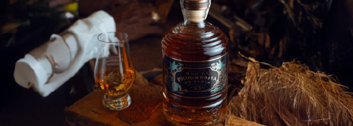 fles en een glas rum op een verhoogde houten pot.