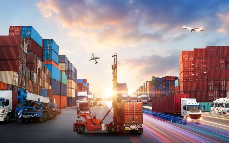 Containerschepen vervoeren vrachtcontainers bij zonsondergang, met vliegende vliegtuigen in de lucht.
