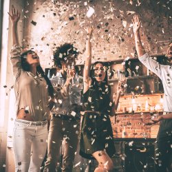 People are celebrating, throwing confetti into the air, standing in a bright, spacious room.