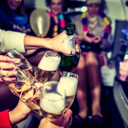 Glasses are clinked, champagne is poured, in a festive limousine with people celebrating.